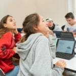 Zwei Teenage Mädchen und zwei Jungs passen ganz konzentriert in einer Programmierlektion auf.