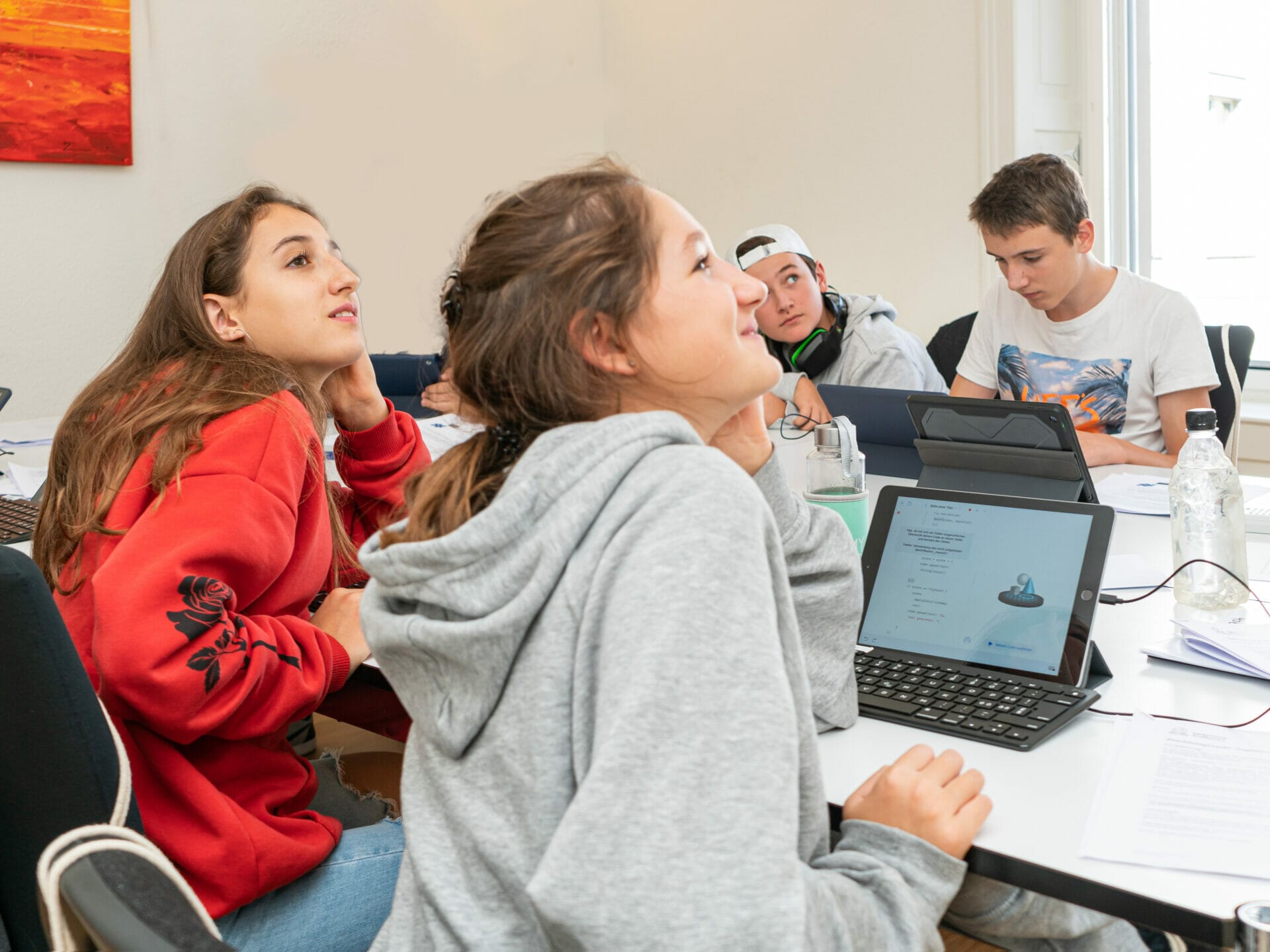 Zwei Teenage Mädchen und zwei Jungs passen ganz konzentriert in einer Programmierlektion auf.