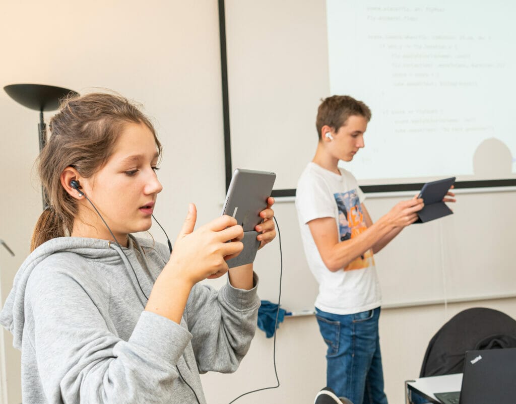 Zwei Teenager, ein Junge und ein Mädchen, halten je ein iPad und erforschen damit die Augmented Reality.