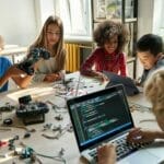 Programmieren lernen in Kleingruppen: Kinder sitzen am Tisch und programmieren Roboter