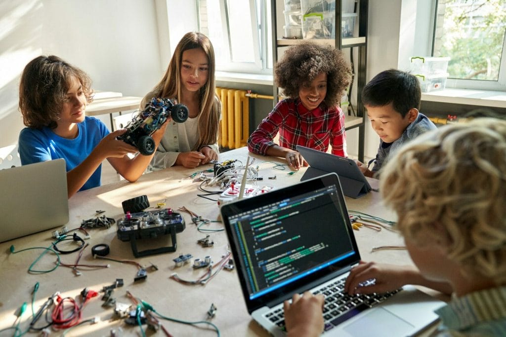 Programmieren lernen in Kleingruppen: Kinder sitzen am Tisch und programmieren Roboter