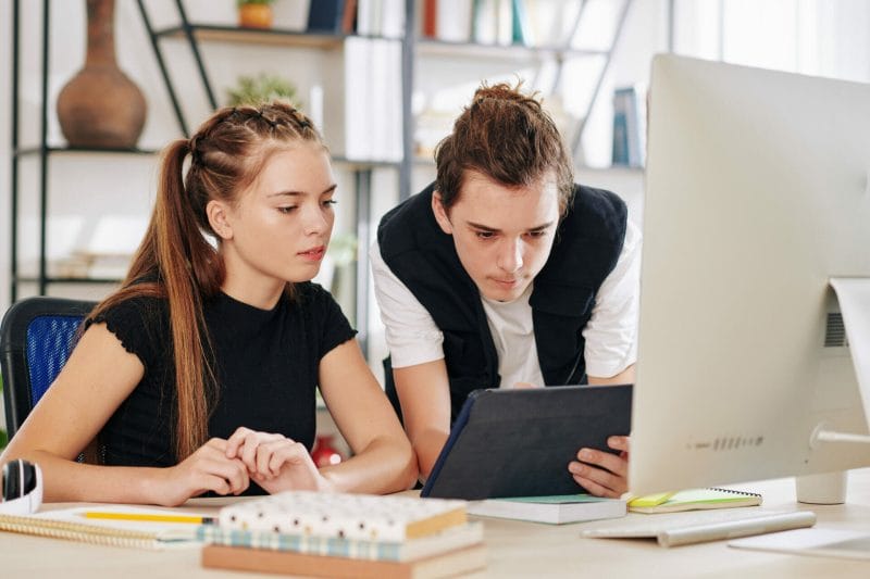 Zwei junge Berufstätige arbeiten gemeinsam an einem Computerarbeitsplatz, um das Programmieren zu lernen.