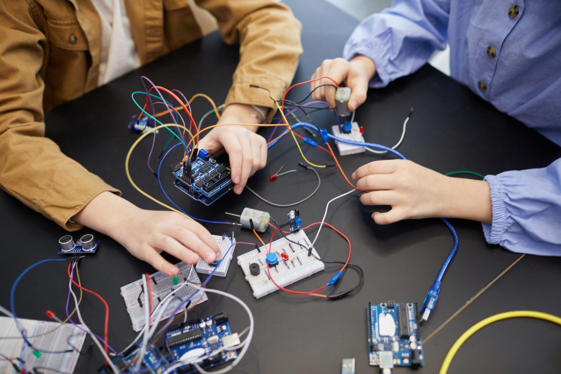 Draufsicht auf nicht erkennbare Kinder, die im Technikunterricht in der Schule Roboter bauen und mit elektrischen Schaltkreisen experimentieren